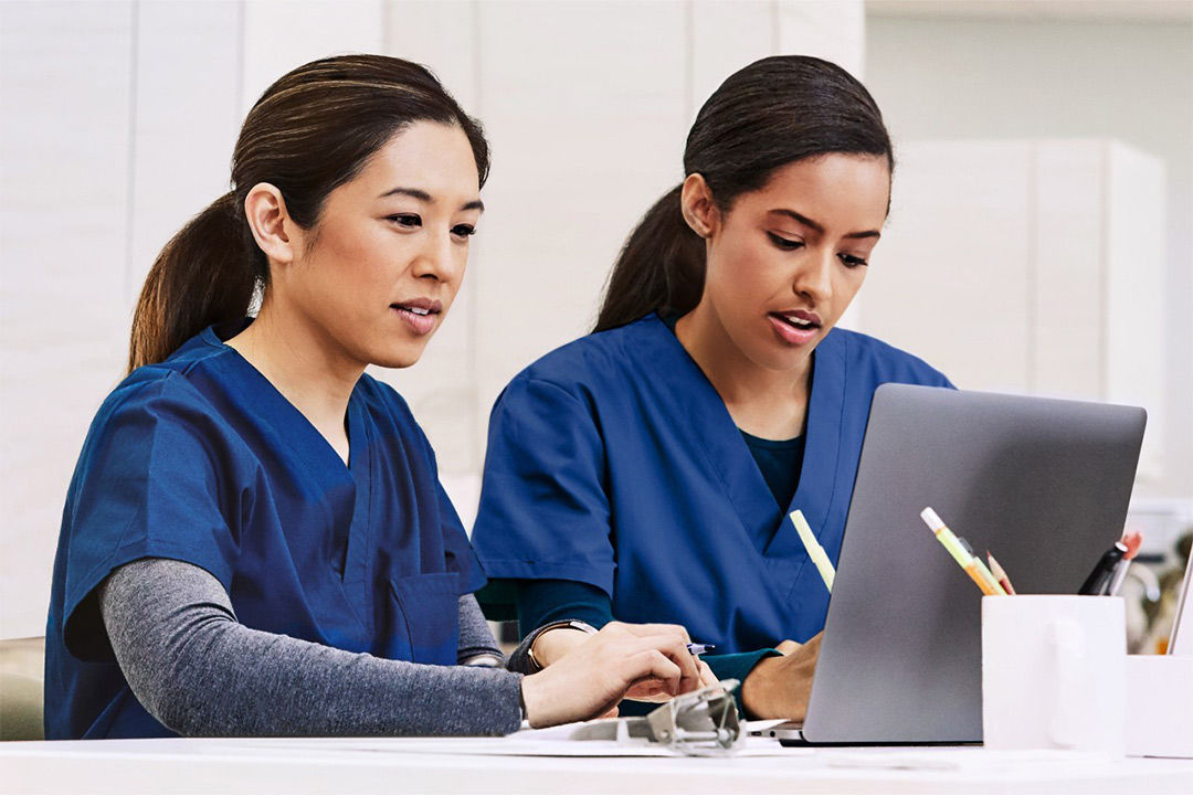 Two doctors taking notes on laptop